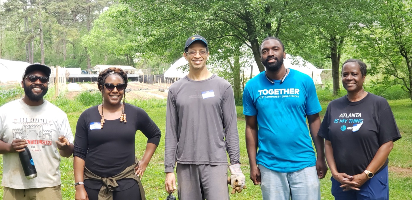 Five community volunteers standing together at a neighborhood garden